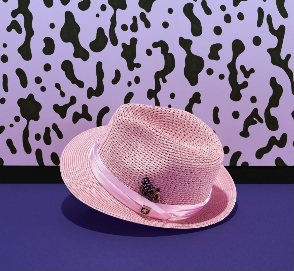 Shop Stacy Adams hats featuring a pink fedora in front of a purple spotted background.